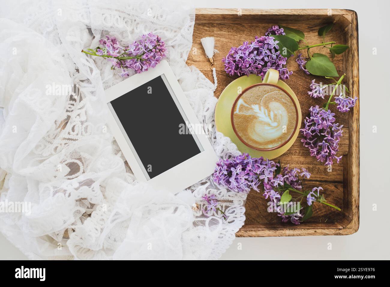 Sommer- oder Frühjahrsheim gemütliche Komposition mit blühenden lilafarbenen Zweigen, E-Book mit Kopierraum und einer Tasse Kaffee. Vorlage für feminine Blogs. Stockfoto