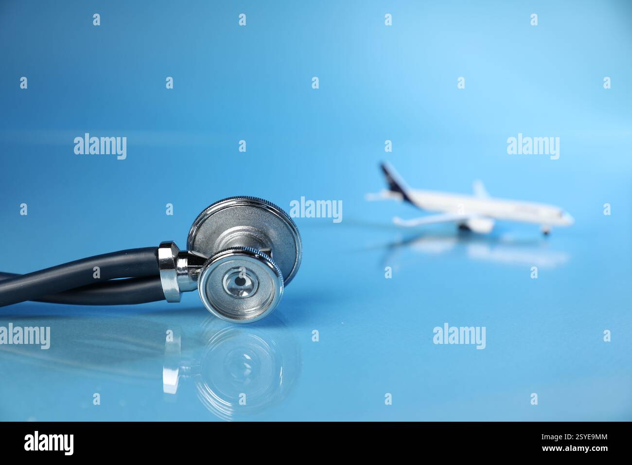 Stethoskop und Flugzeugmodell auf hellblauem Hintergrund, selektiver Fokus Stockfoto
