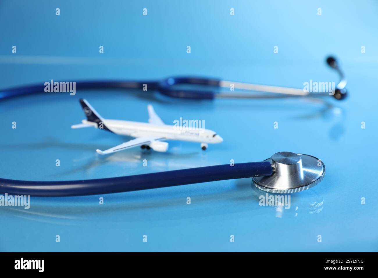 Stethoskop und Flugzeugmodell auf hellblauem Hintergrund, Nahaufnahme Stockfoto