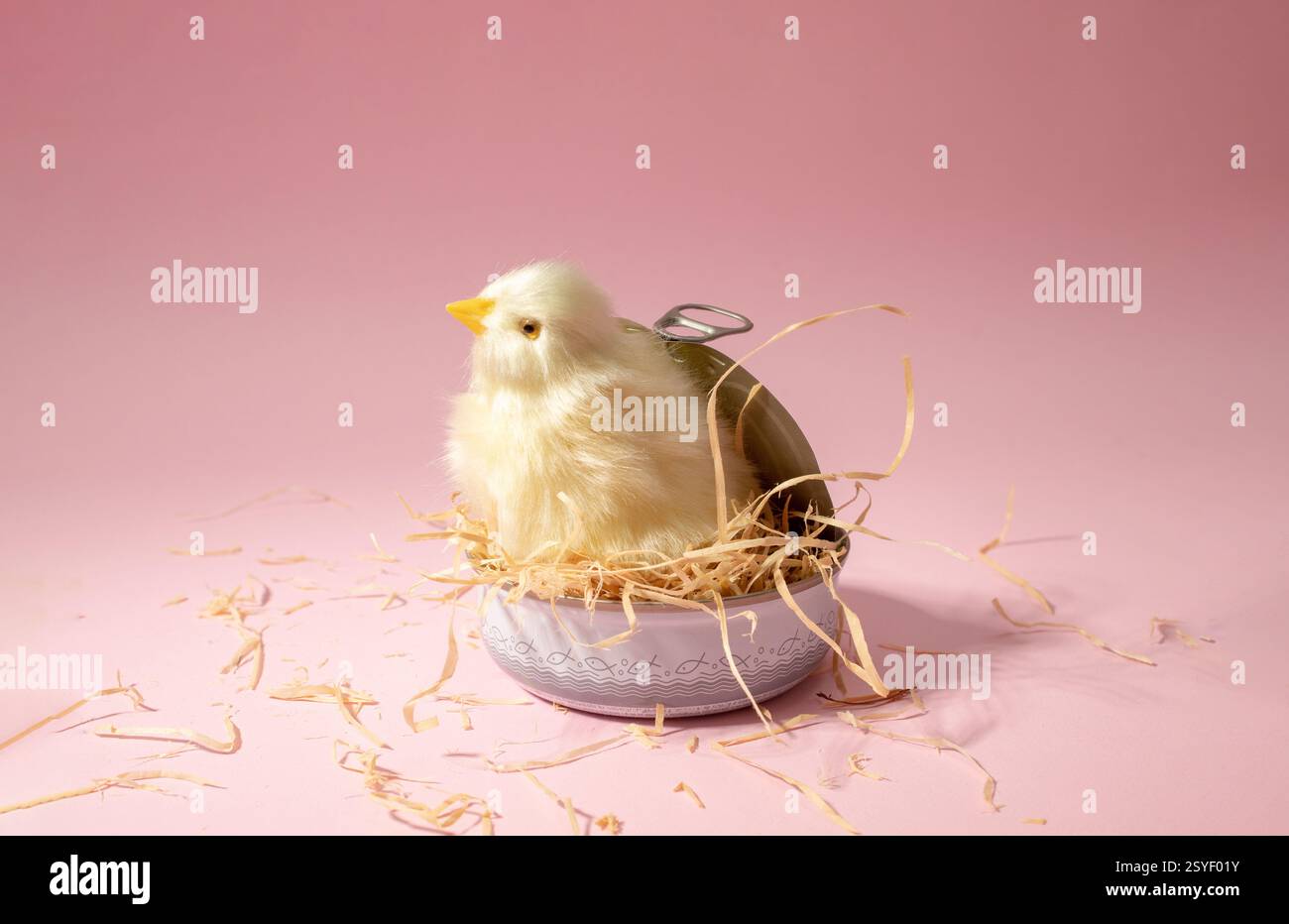 Spielzeug-Huhn in einem Nest in einer Dose auf pastellrosa Hintergrund. Umweltschutzkonzept Stockfoto