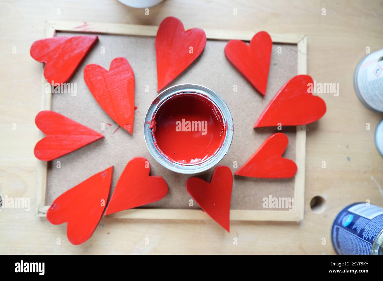 Hölzerne Herzen, rot lackiert, um den Valentinstag zu feiern. Roter Farbtopf. Stockfoto