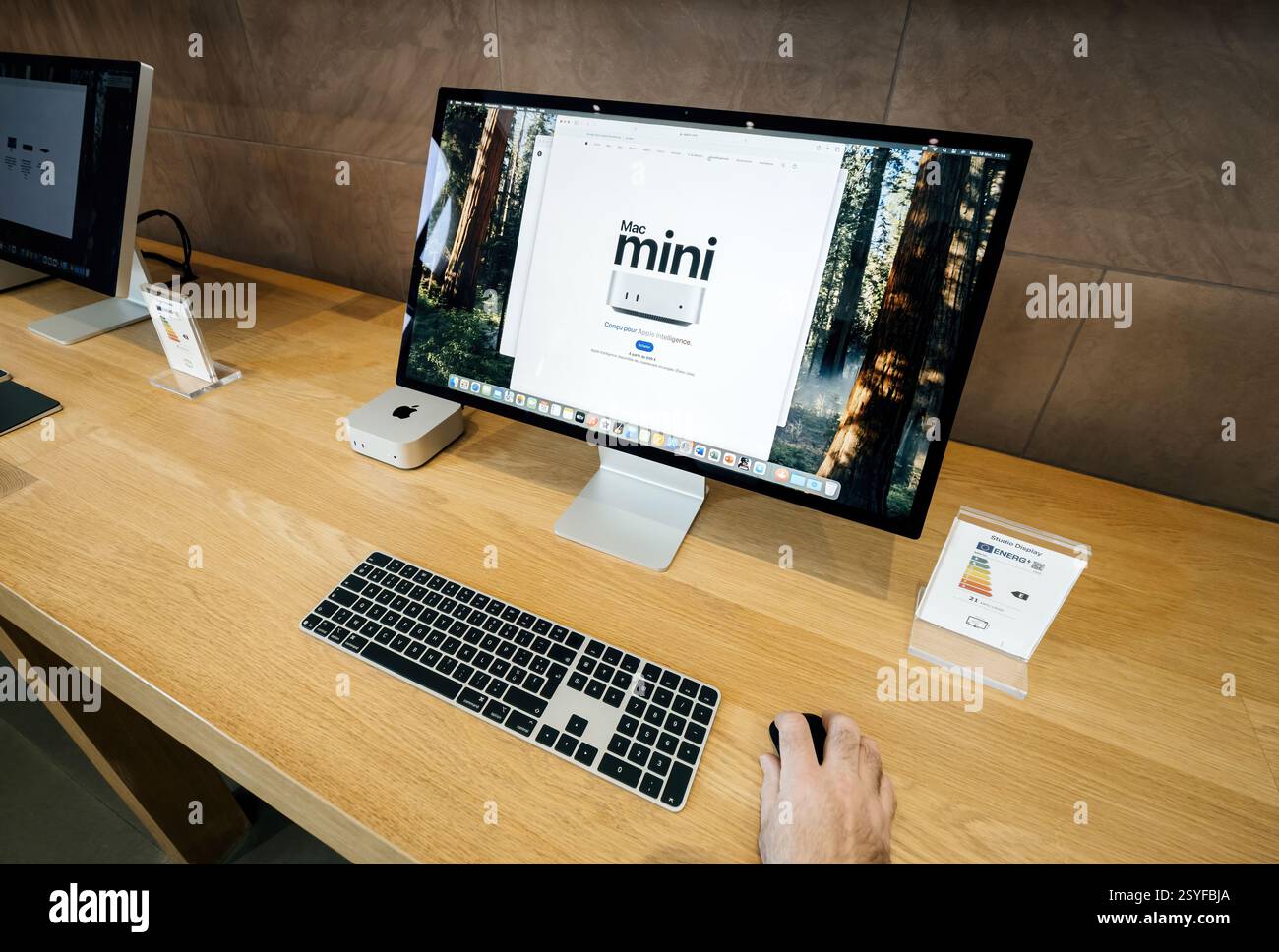 Paris, Frankreich - 18. Februar 2025: Ein Display zeigt einen Mac Mini neben einer Apple-Tastatur und -Maus, und ein Studio Display-Monitor zeigt die Mac's Stockfoto