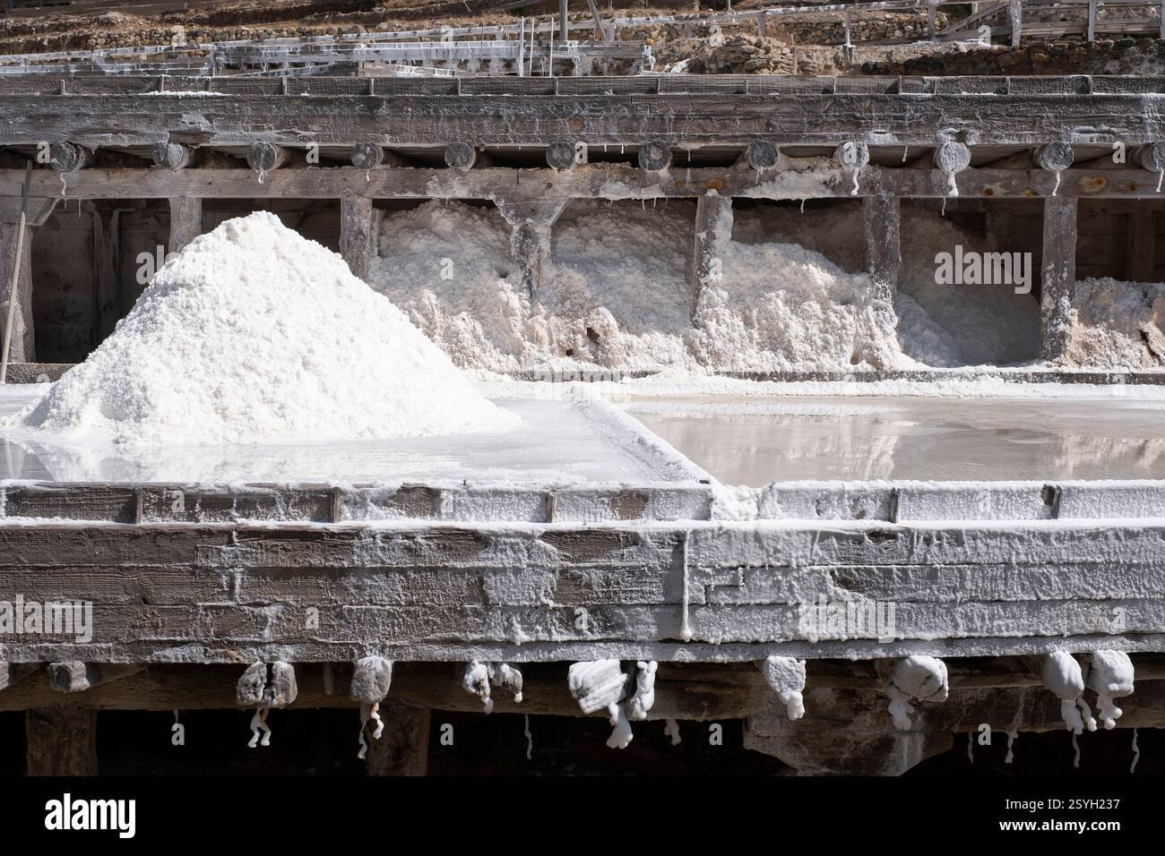 Ein Salzhaufen, der durch die Verdunstung von Wasser in einem Salzbergwerk im Binnenland entsteht, mit Verdunstungsteichen auf Holzterrassen in verschiedenen Ebenen, Añan Stockfoto