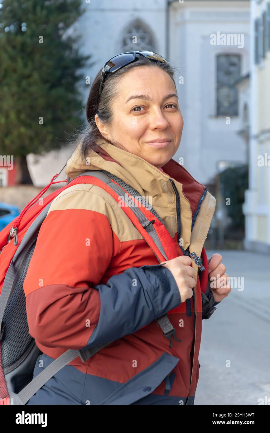 Eine Frau mit Rucksack erkundet eine Altstadt am Fuße der Alpen Stockfoto