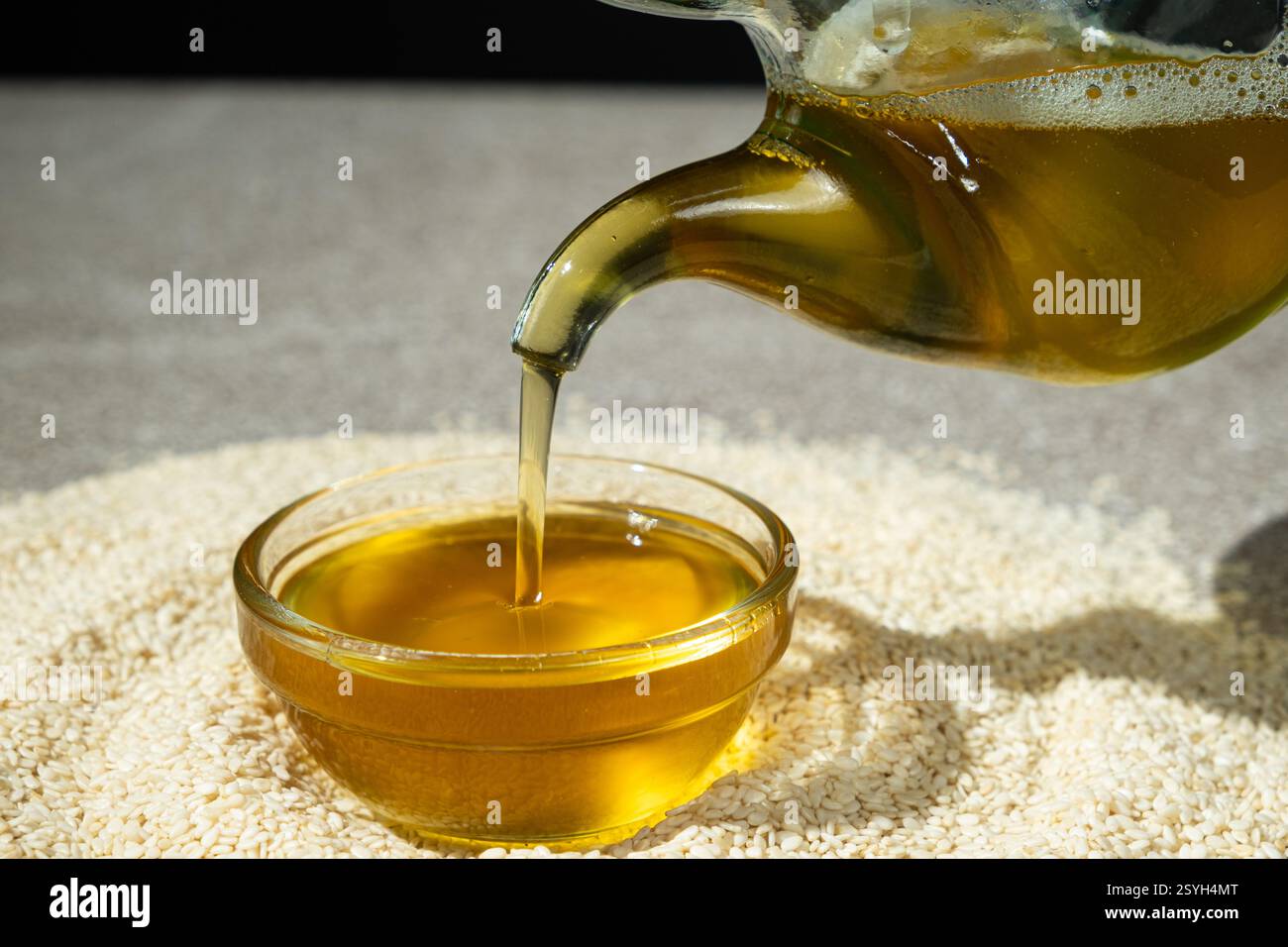 Unraffiniertes kaltgepresstes Sesamöl in eine Glasschale gegossen. Stockfoto