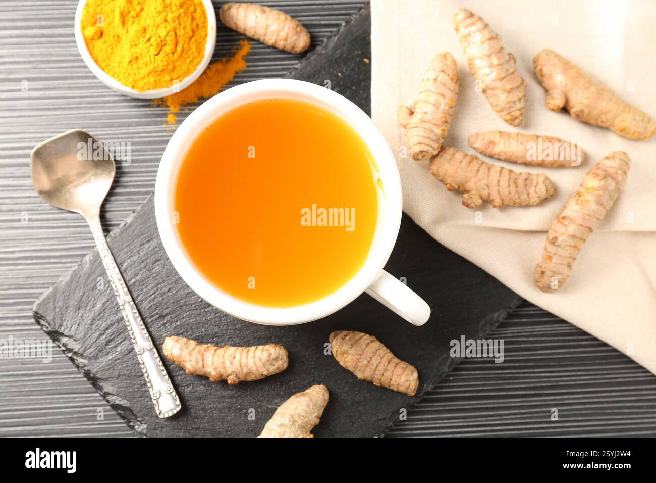 Aromatischer Kurkuma-Tee, Pulver und Rhizome auf schwarzem Tisch, flach gelegen Stockfoto