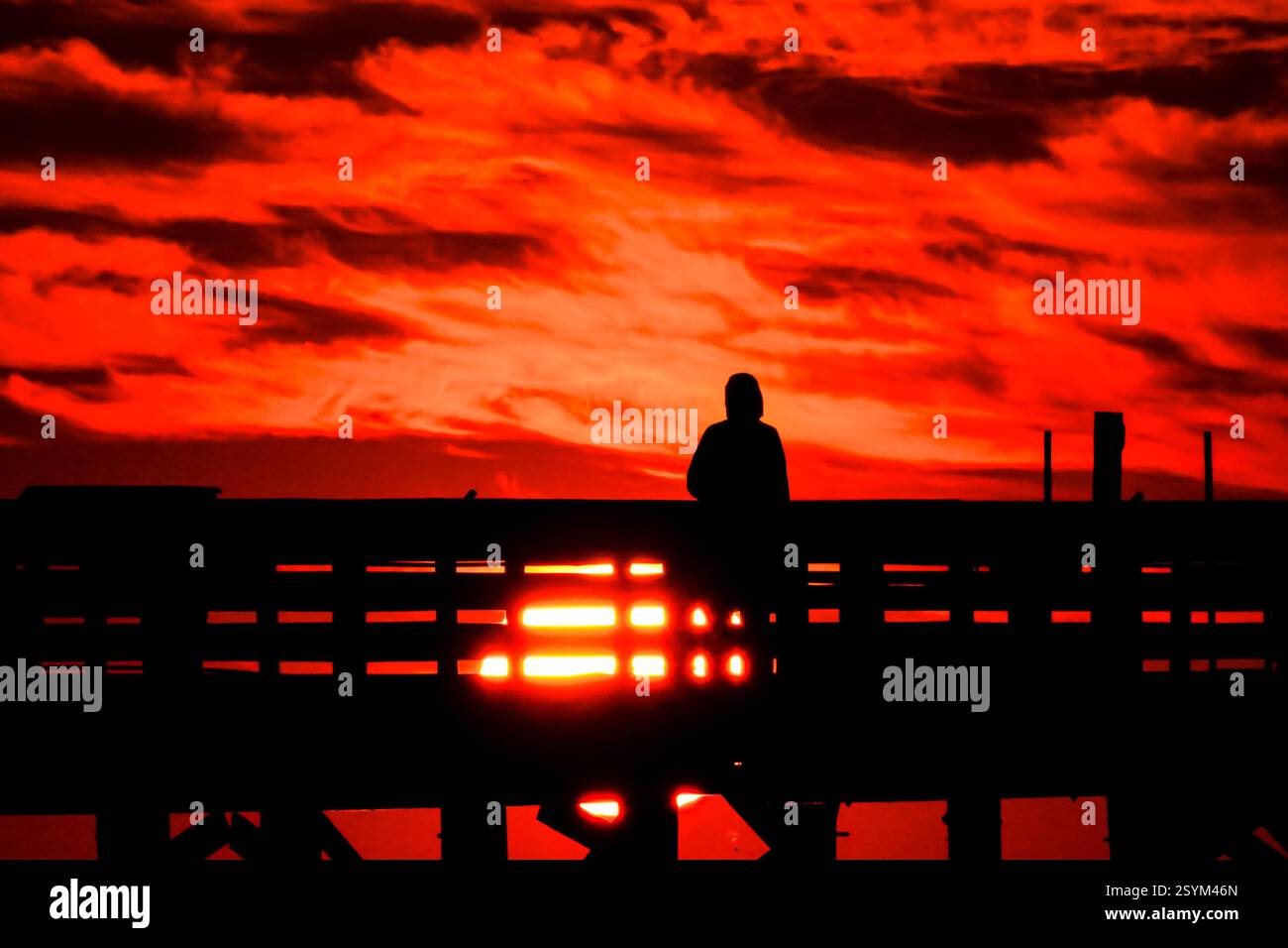 Isle Of Palms, Usa. März 2025. Eine Person, die vom Sonnenaufgang über dem Atlantischen Ozean geschildert wird, beobachtet vom Isle of Palms Pier am Front Beach, 1. März 2025 in Isle of Palms, South Carolina. Eine allmähliche Erwärmung bis in die 70er Jahre wird sich nach einem harten Winter im Tiefland fortsetzen. Quelle: Richard Ellis/Richard Ellis/Alamy Live News Stockfoto