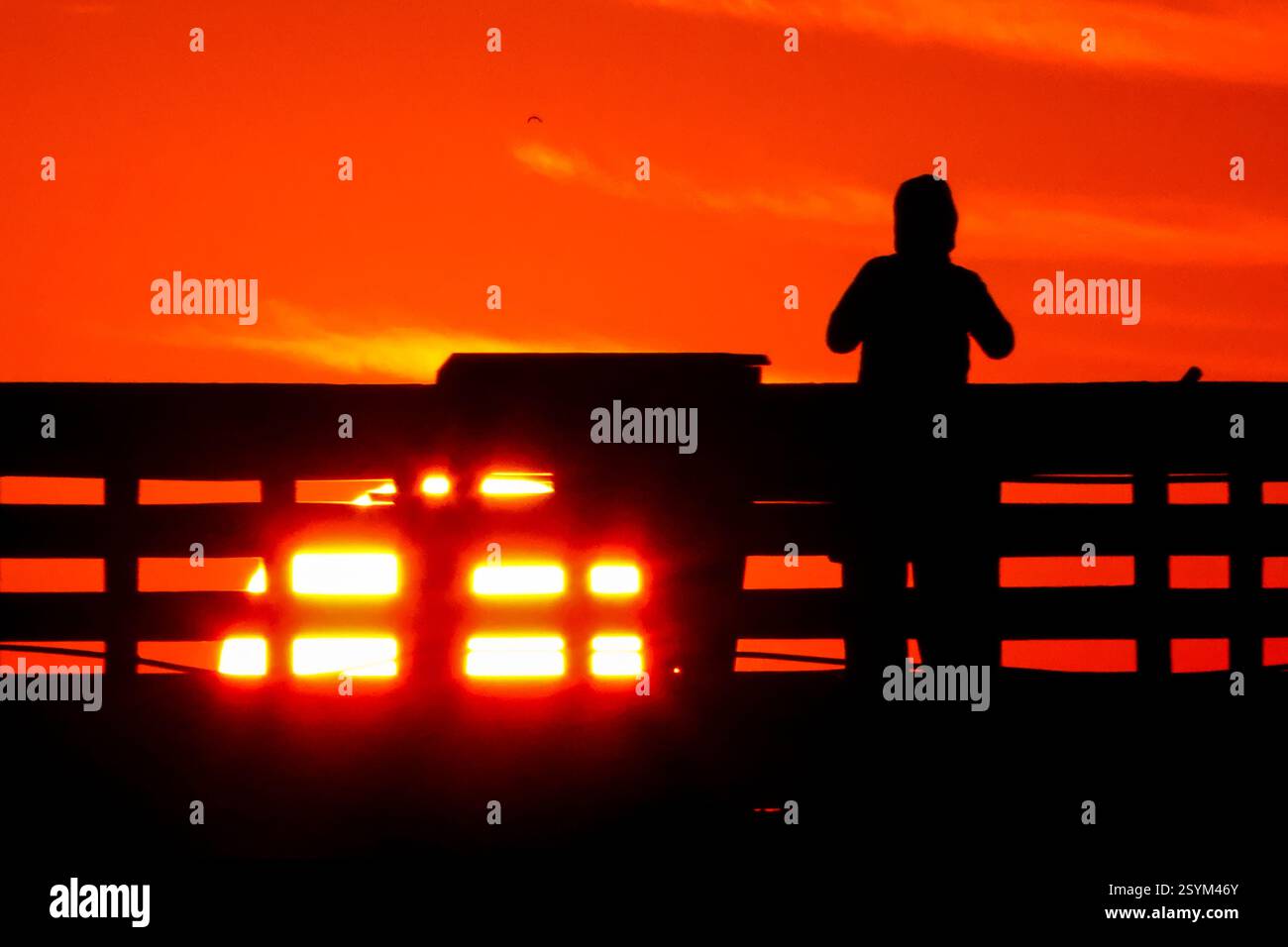 Isle Of Palms, Usa. März 2025. Eine Person, die vom Sonnenaufgang über dem Atlantischen Ozean geschildert wird, beobachtet vom Isle of Palms Pier am Front Beach, 1. März 2025 in Isle of Palms, South Carolina. Eine allmähliche Erwärmung bis in die 70er Jahre wird sich nach einem harten Winter im Tiefland fortsetzen. Quelle: Richard Ellis/Richard Ellis/Alamy Live News Stockfoto