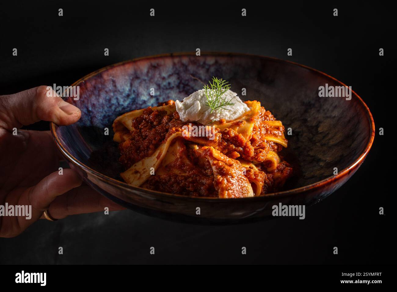 Ein italienisches Gourmet-Pastagericht mit reichhaltiger Fleischsauce und Ricotta, serviert in einer rustikalen Keramikschale. Eine perfekte Mahlzeit für Liebhaber authentischer italienischer Küche Stockfoto