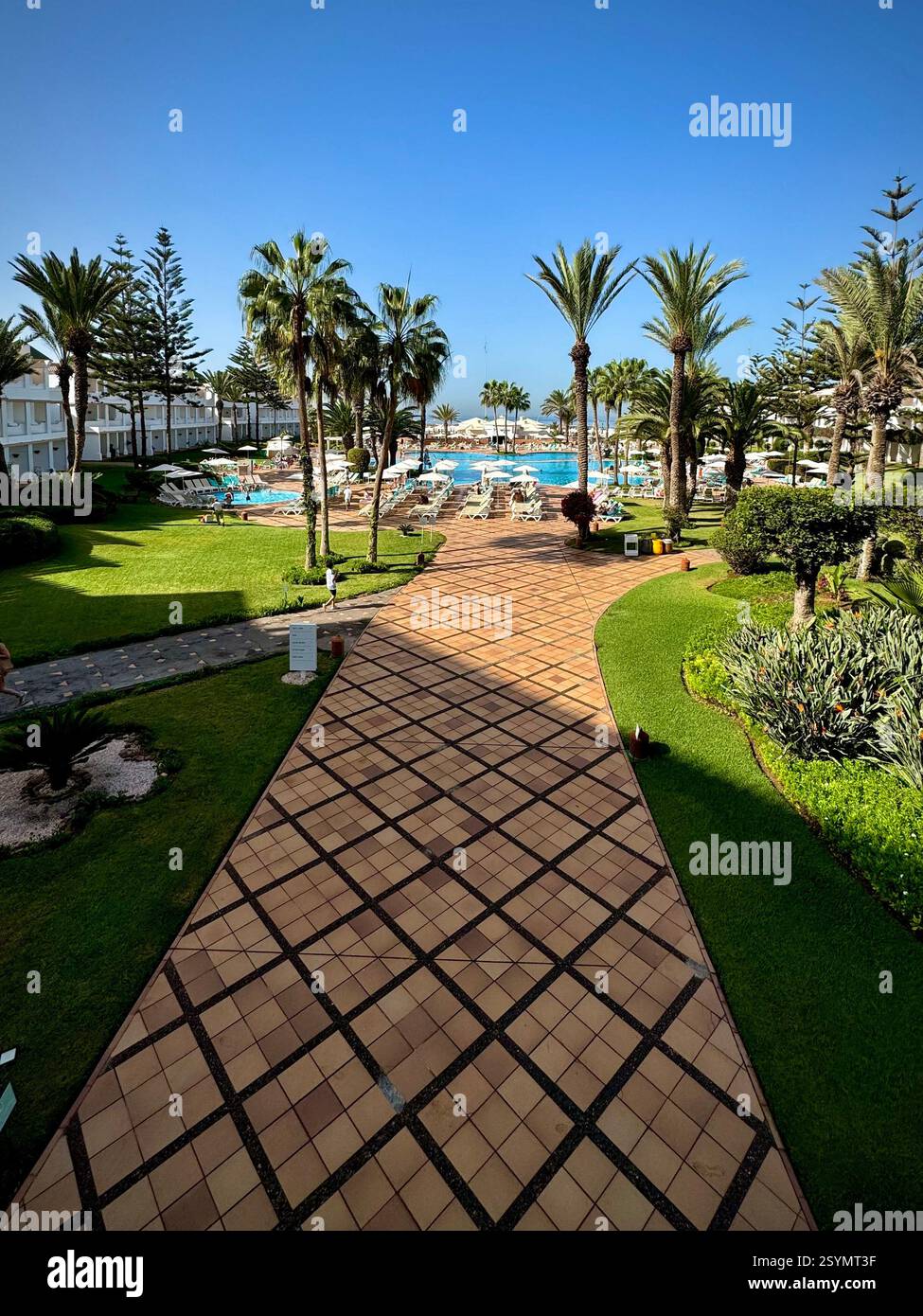 Blick auf Gärten und Pool mit hellblauem Himmel, Iberostar Wellen, Founty Beach Hotel, Agadir, Marokko - Smartphone-aufgenommenes Stockfoto