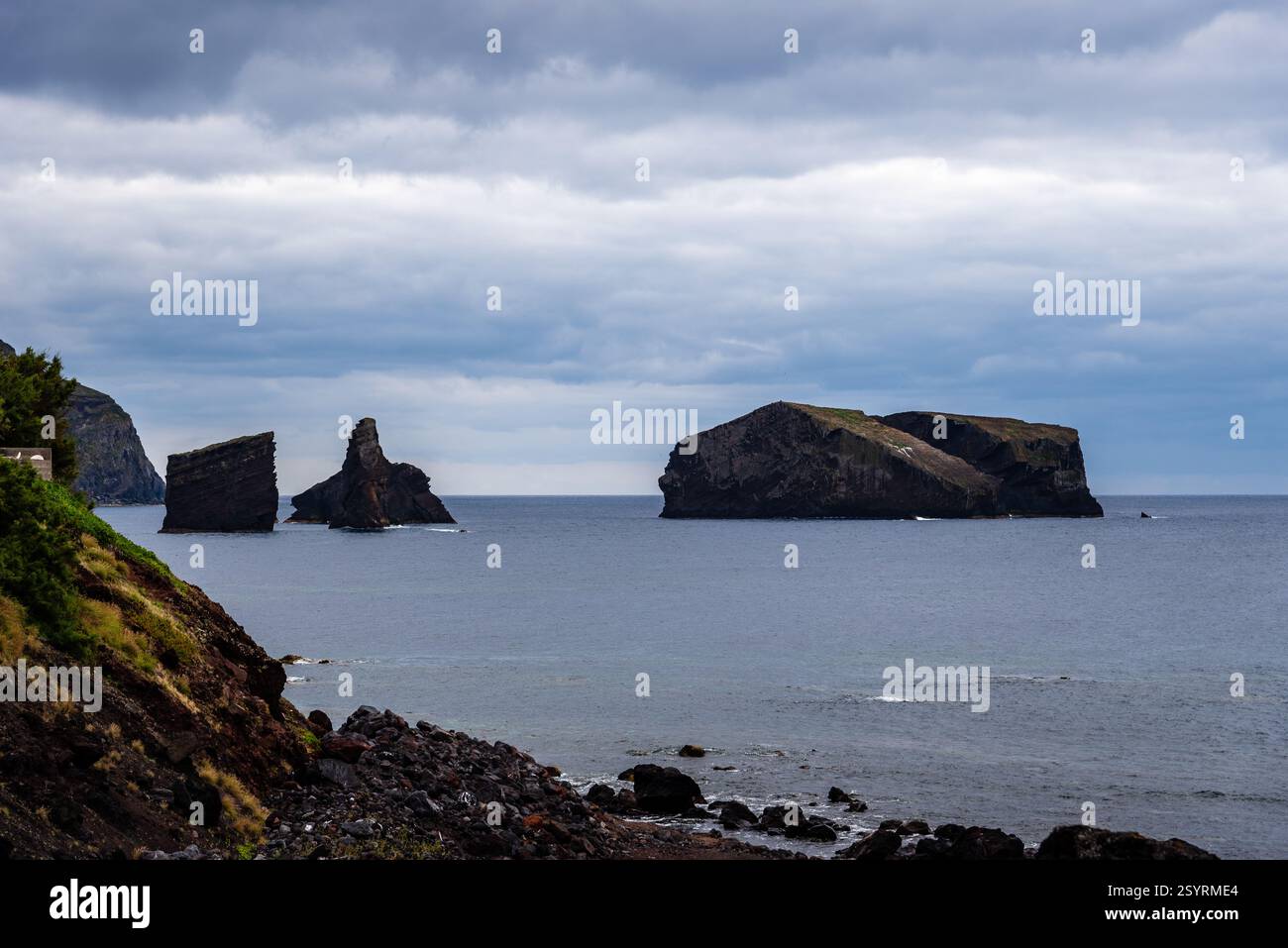 Zwei felsige Inselchen stehen hoch im Atlantik unter einem bewölkten Himmel und bilden eine dramatische Meereslandschaft in der Nähe von Praia dos Mosteiros auf den Azoren. Stockfoto