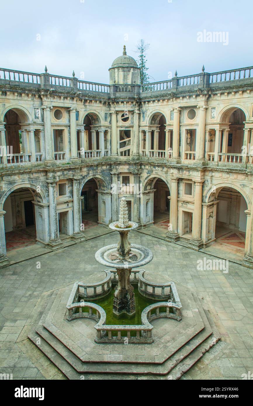 Fesselnder Blick aus der Vogelperspektive auf einen historischen Klosterhof mit symmetrischem Layout mit bogenförmigen Kreuzgängen, einem zentralen Brunnen und üppigem Grün Stockfoto