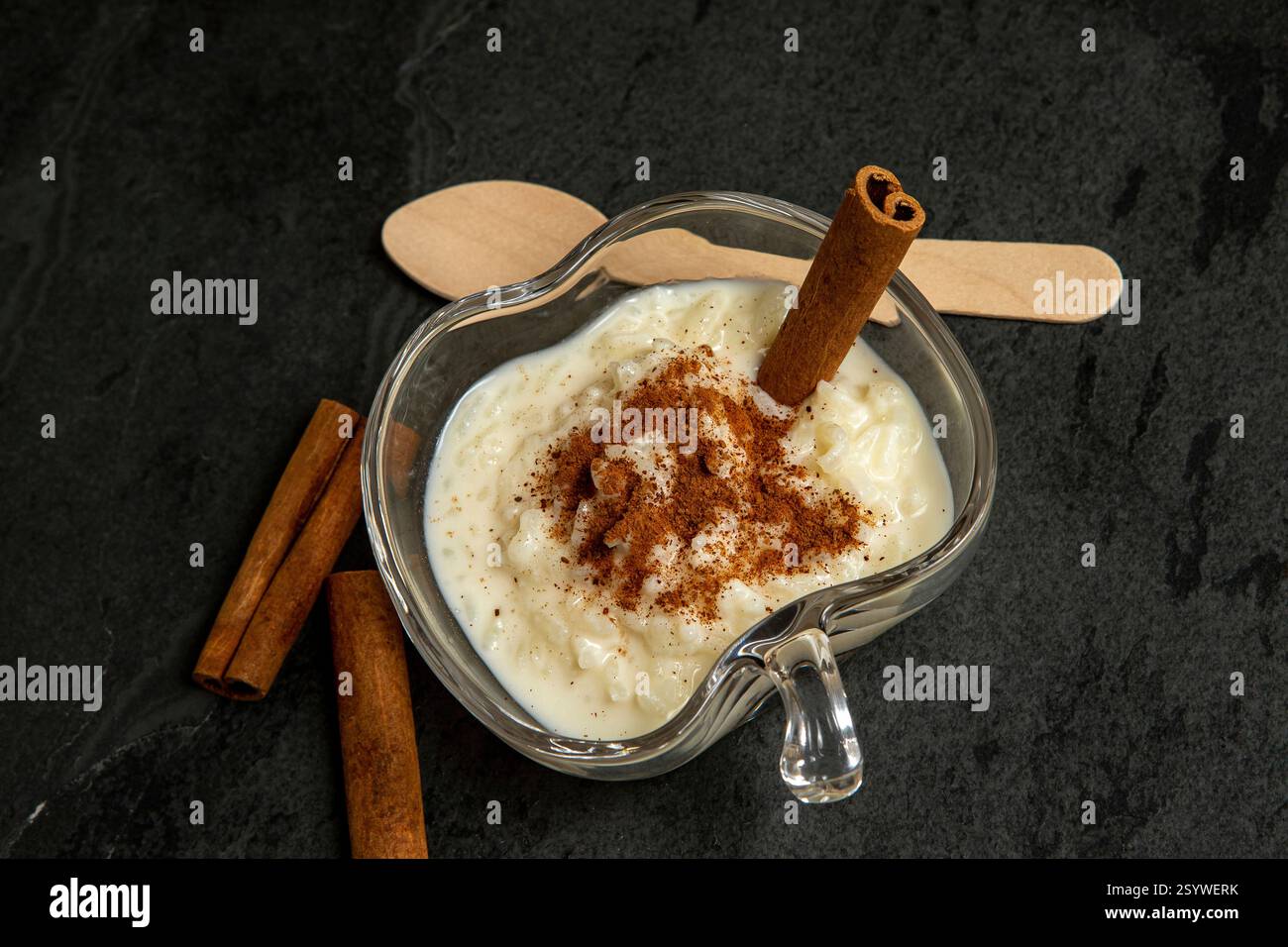 Traditionelles brasilianisches Dessert aus Reis und Kondensmilch, genannt Arroz Doce, dekoriert mit Zimt auf dunklem Hintergrund Stockfoto