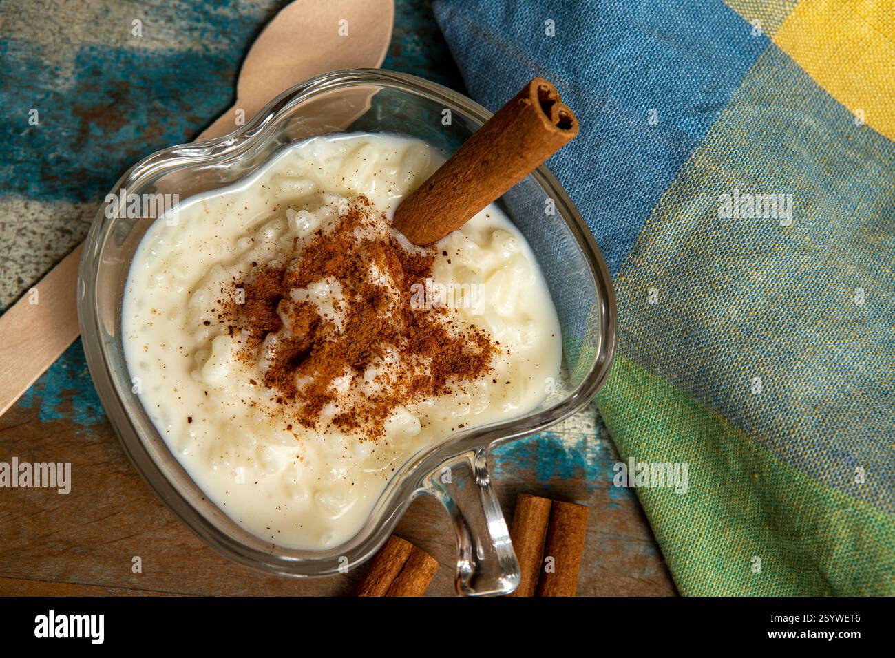 Traditionelles brasilianisches Dessert aus Reis und Kondensmilch, genannt Arroz Doce, dekoriert mit Zimt auf farbenfrohem Hintergrund Stockfoto