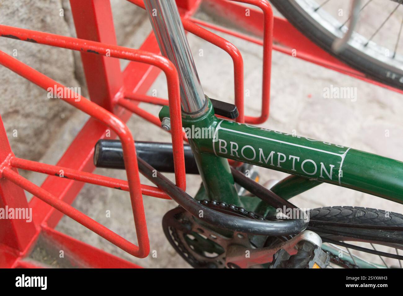 Brompton-Fahrrad parkt in einem roten Fahrradständer. Wahrscheinlich in einer Stadt, die Lage ist nicht genau zu identifizieren. Stockfoto