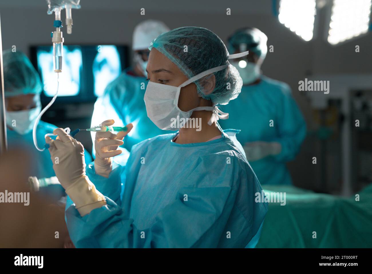 Birassische Chirurg in Operationskittel mit Tropfinfusion im Operationssaal des Krankenhauses Stockfoto