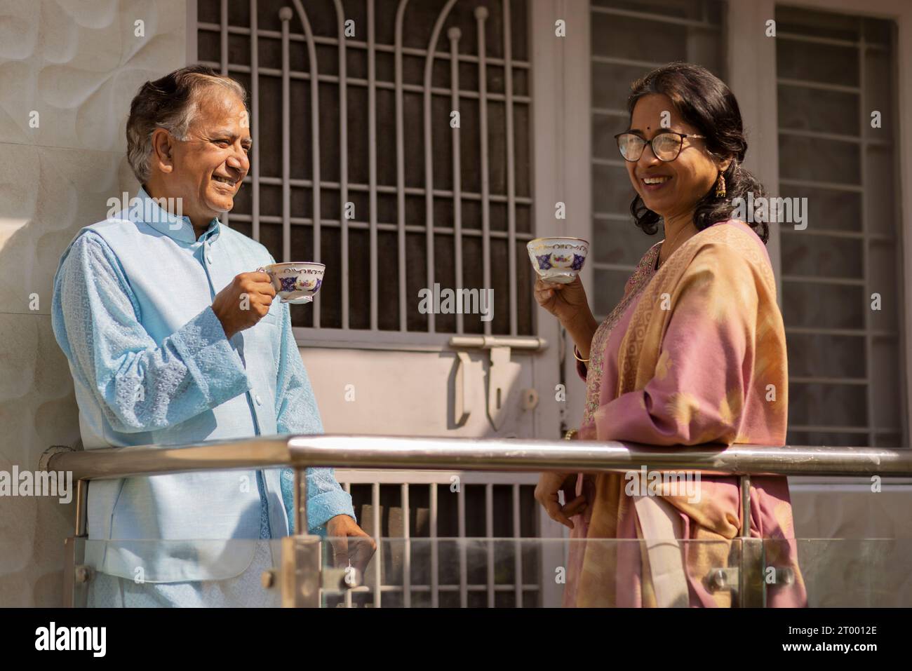 Ein älteres Paar trinkt Tee, während er auf dem Balkon steht Stockfoto