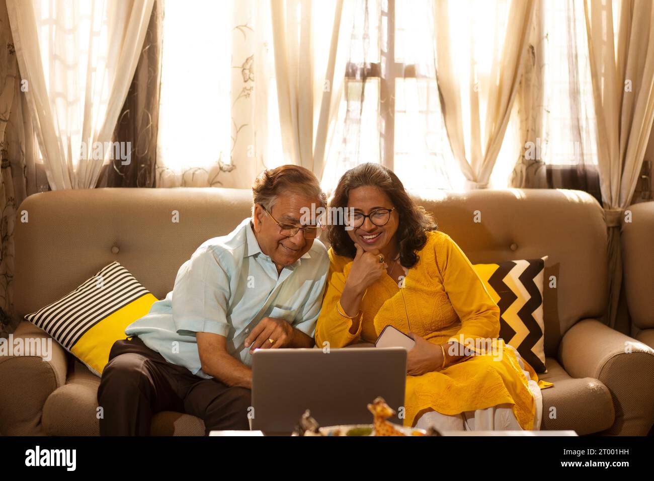 Ein älteres Ehepaar, das im Wohnzimmer zusammen auf dem Sofa sitzt Stockfoto