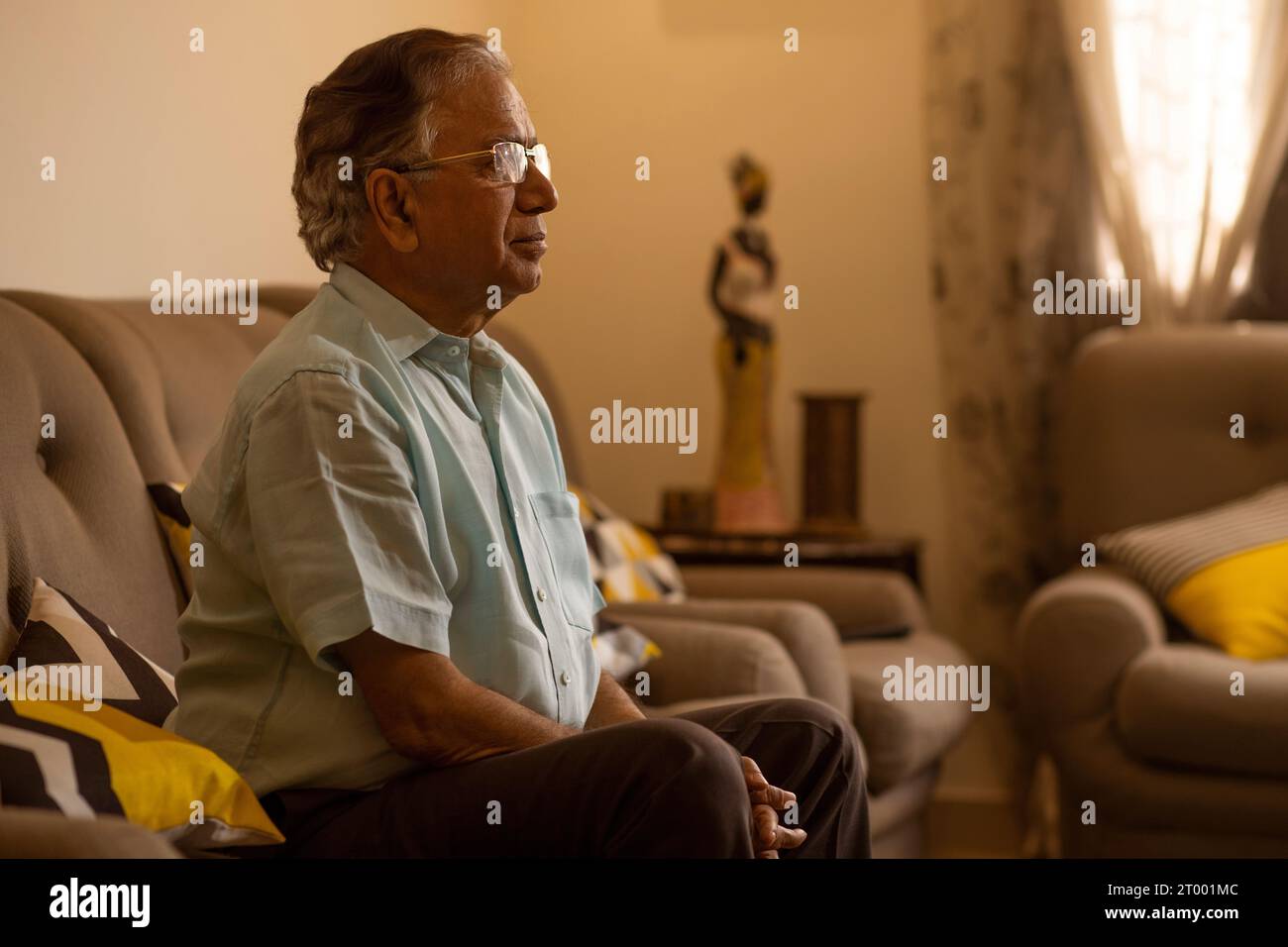 Porträt eines älteren Mannes, der im Wohnzimmer auf dem Sofa sitzt Stockfoto