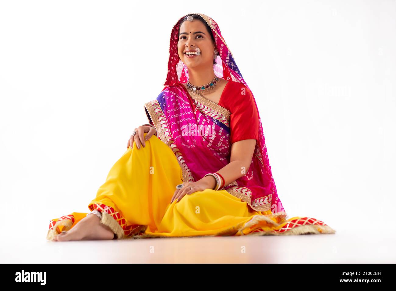 Porträt einer Rajasthani-Frau, die mit weißem Hintergrund sitzt Stockfoto