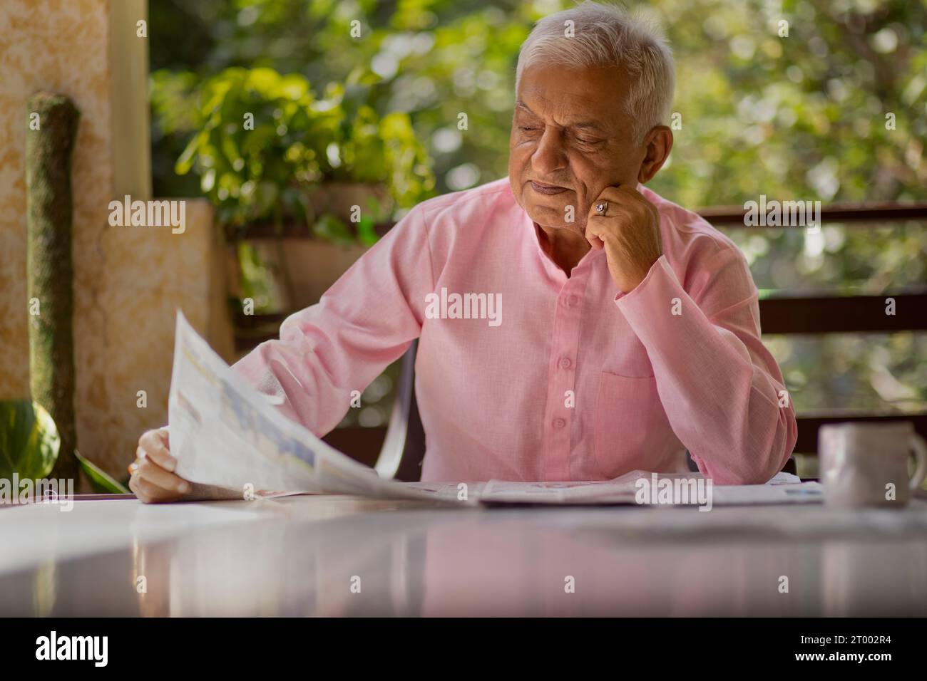 Porträt eines älteren Mannes, der auf dem Balkon Zeitung liest Stockfoto
