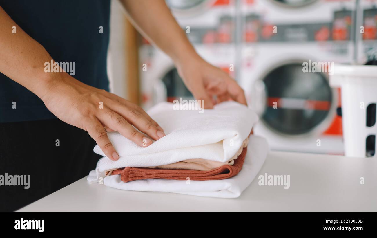 Hausmann mit Korb und schmutziger laundryÂ gewaschener Kleidung im Waschraum. Waschen machineÂ im Wäschereigeschäft Stockfoto