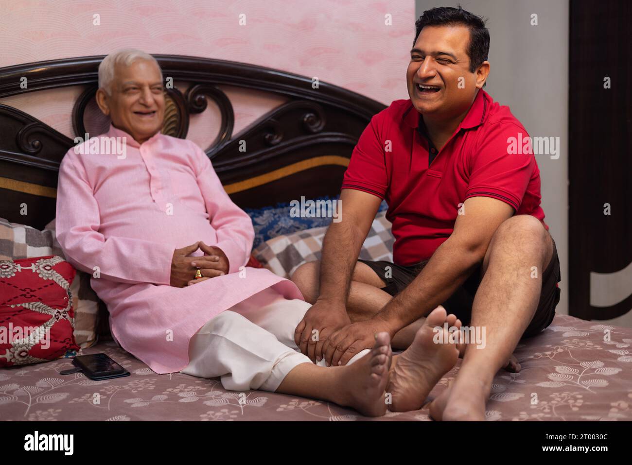 Mann massiert die Beine seines alten Vaters Stockfoto