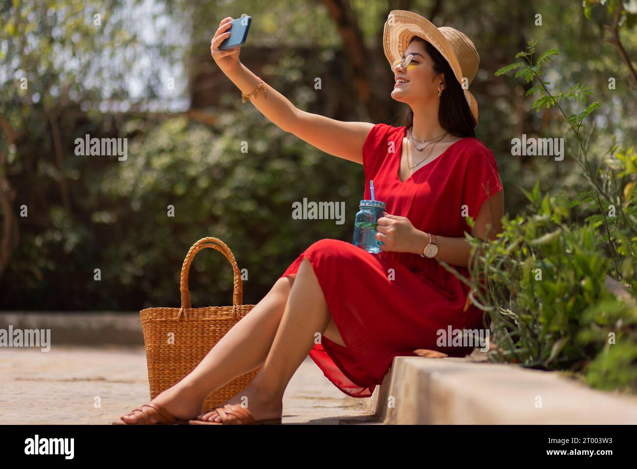 Frau macht Selfie, während sie im Park sitzt Stockfoto