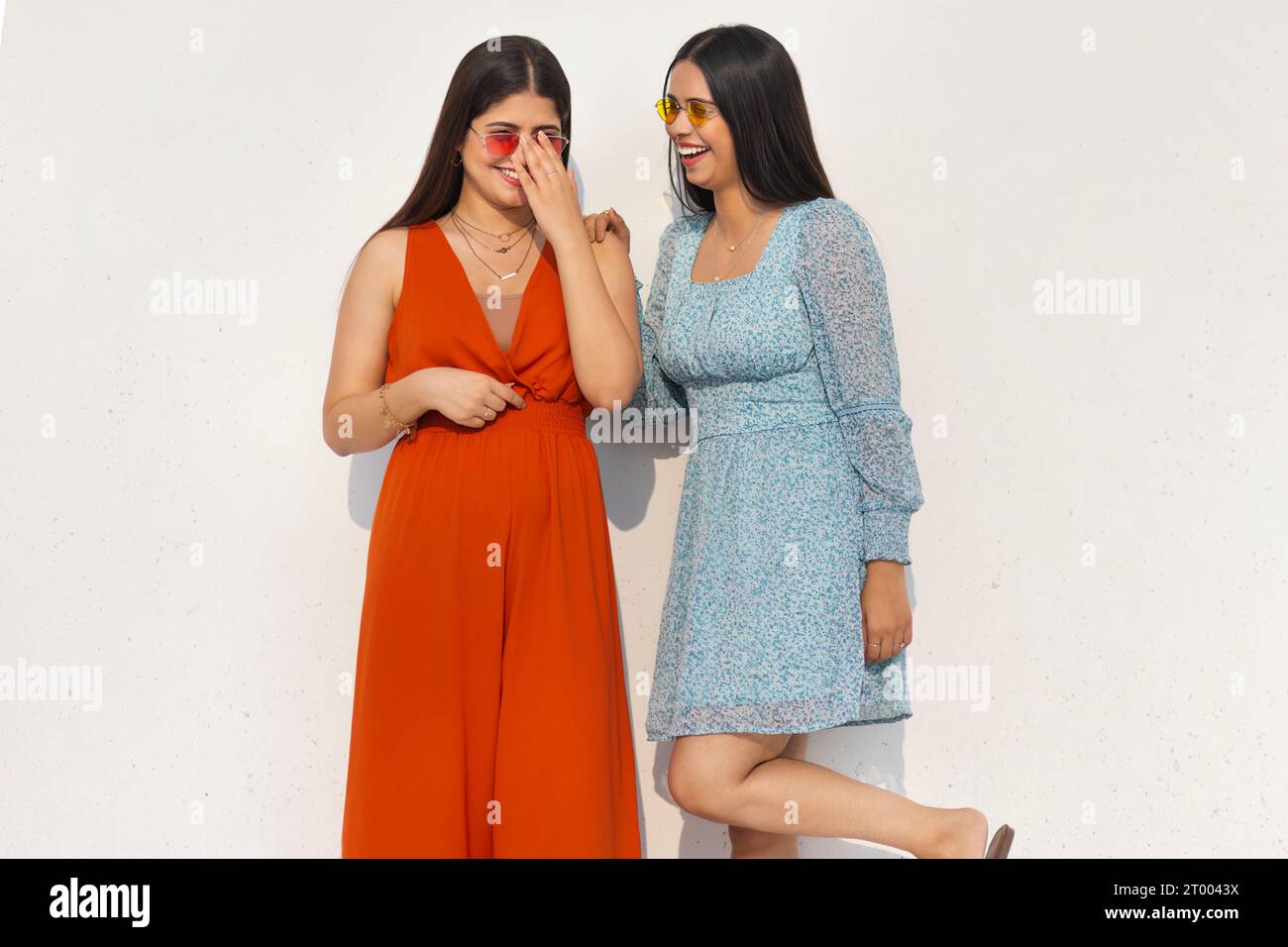 Zwei junge Frauen mit Sonnenbrille stehen zusammen vor weißem Hintergrund Stockfoto