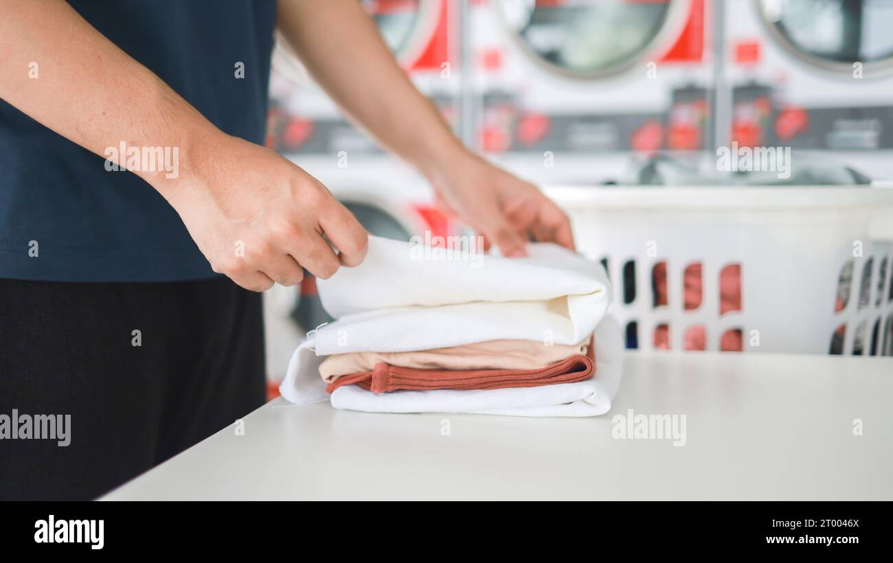 Hausmann mit Korb und schmutziger laundryÂ gewaschener Kleidung im Waschraum. Waschen machineÂ im Wäschereigeschäft Stockfoto