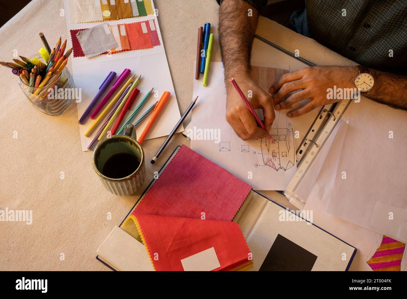Ein junger Profi, der in seinem Atelier an Herrenmode-Designs arbeitet Stockfoto