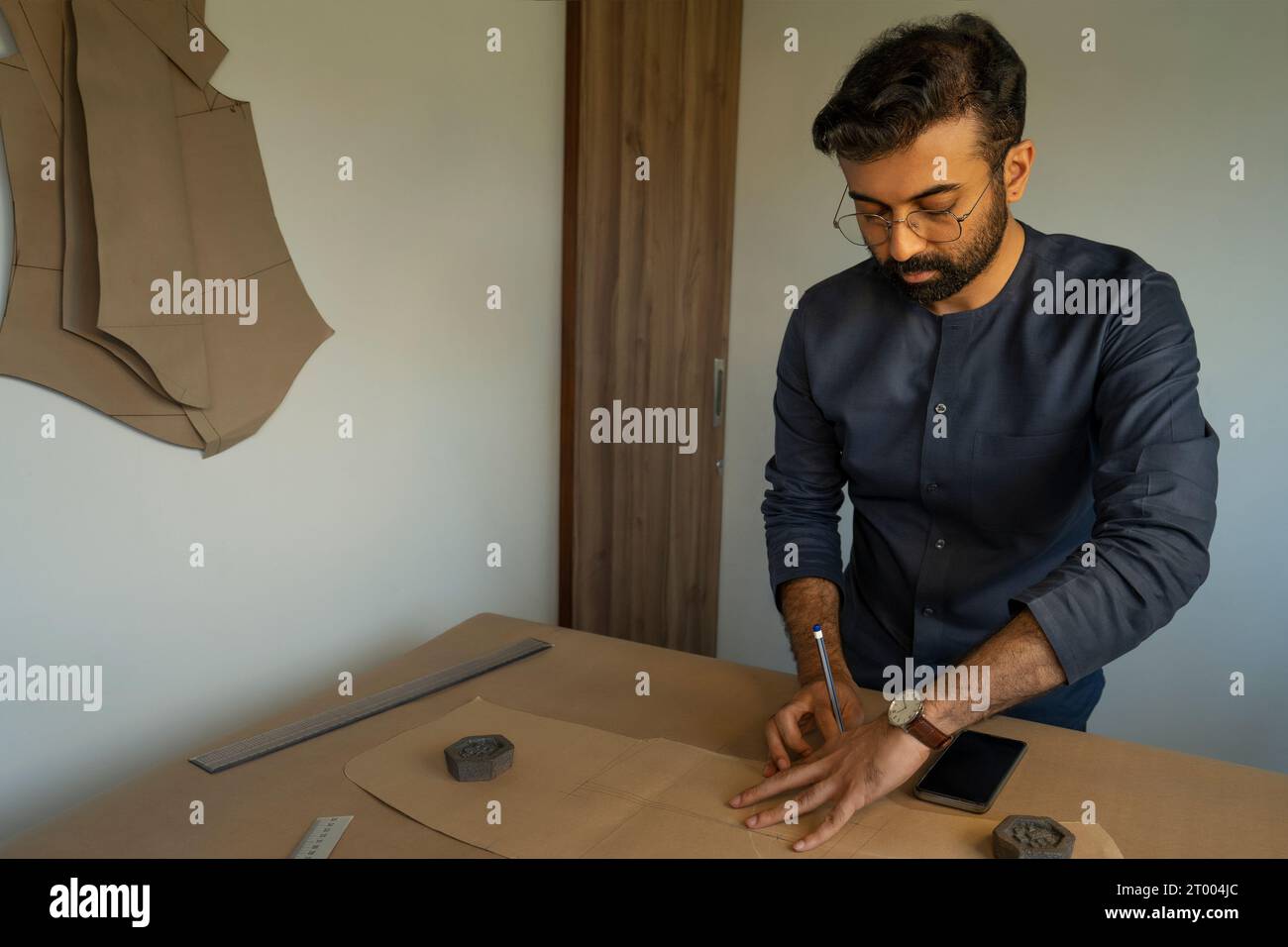Ein männlicher Designer, der Muster für eine Herrenmode-Kollektion in seinem Atelier herstellt Stockfoto