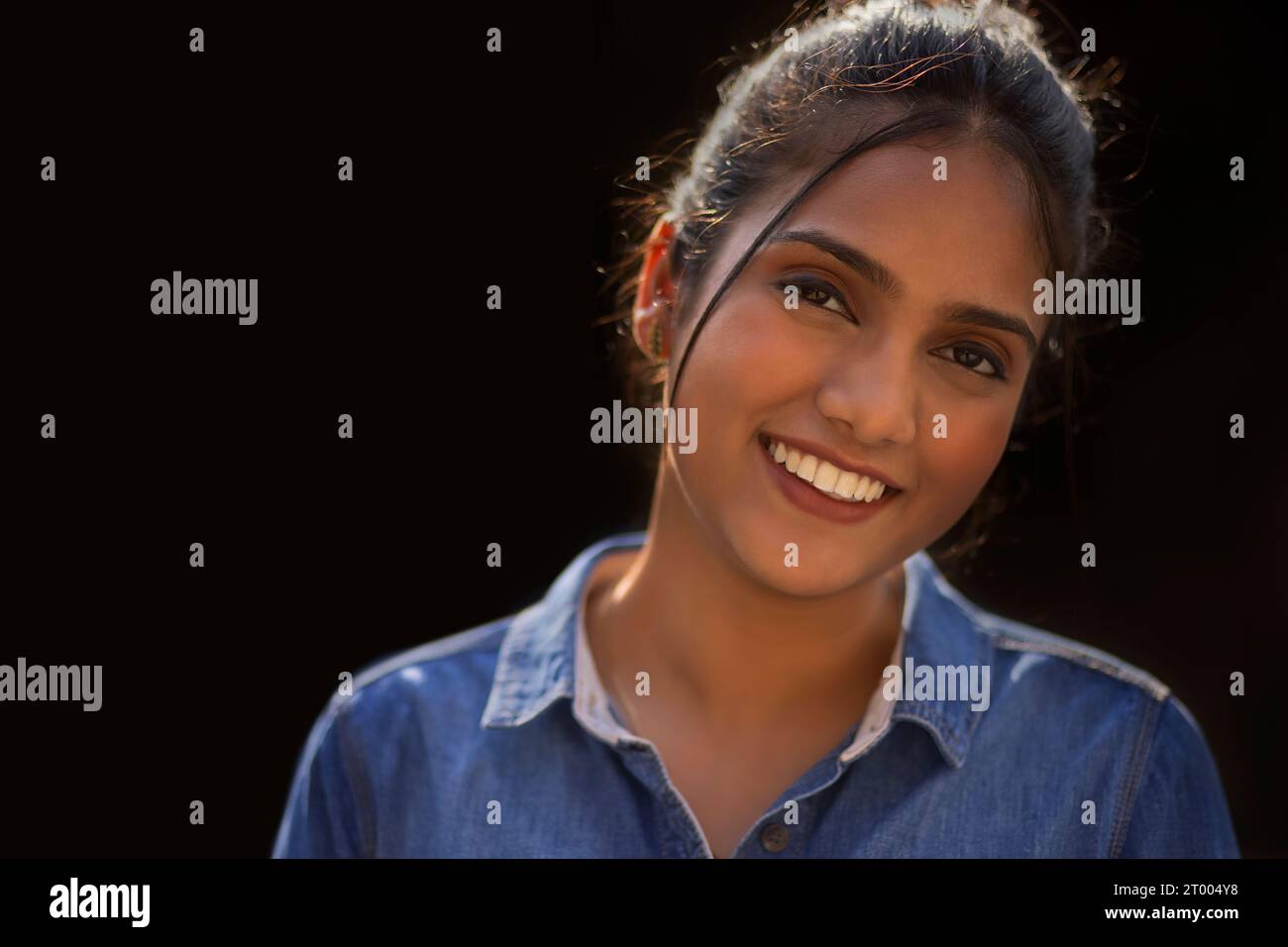 Nahporträt einer lächelnden jungen Frau vor schwarzem Hintergrund Stockfoto