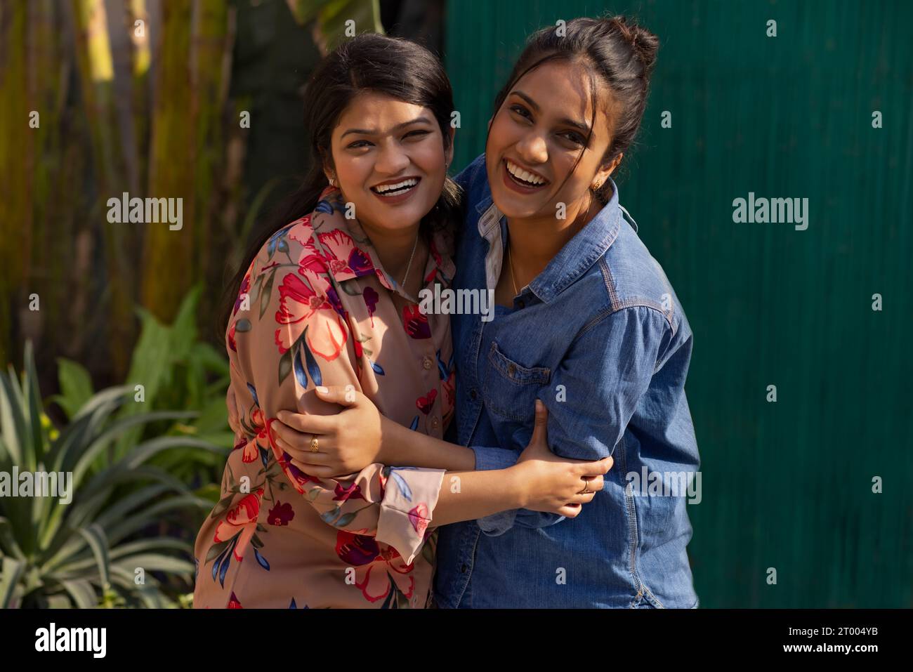 Zwei lächelnde junge Frauen, die sich umarmen Stockfoto