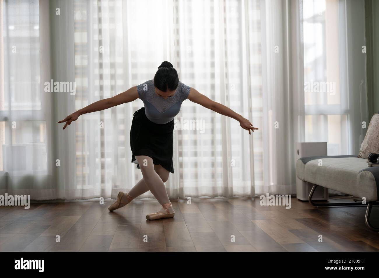 Ein junges Mädchen übt Balletttanzen im Wohnzimmer. Junge Ballerina, die klassische Choreographie praktiziert. Ballettkonzept. Stockfoto