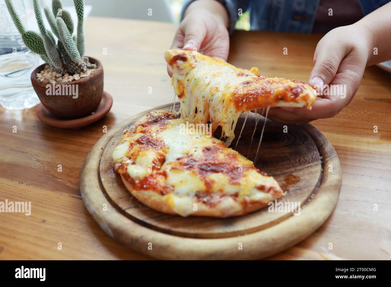 Eine Scheibe frischer, heißer, sehr käsiger vegetarischer Pizza, Mozzarella. Italienische Pizza Margherita in der Hand Stockfoto