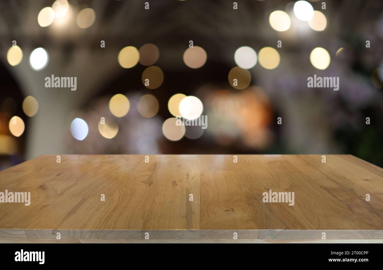 Leerer Holztisch vor abstraktem, verschwommenem Hintergrund des Cafés. Kann zur Anzeige oder Montage Ihrer Produkte verwendet werden.MOC Stockfoto