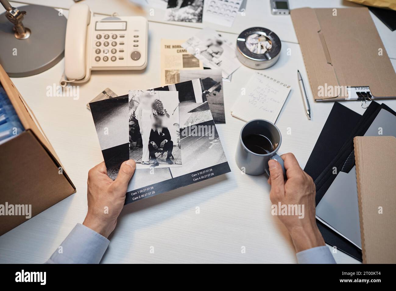 Großansicht eines männlichen Detektivs mit Händen, die Beweisbilder am Schreibtisch halten, Kopierraum Stockfoto