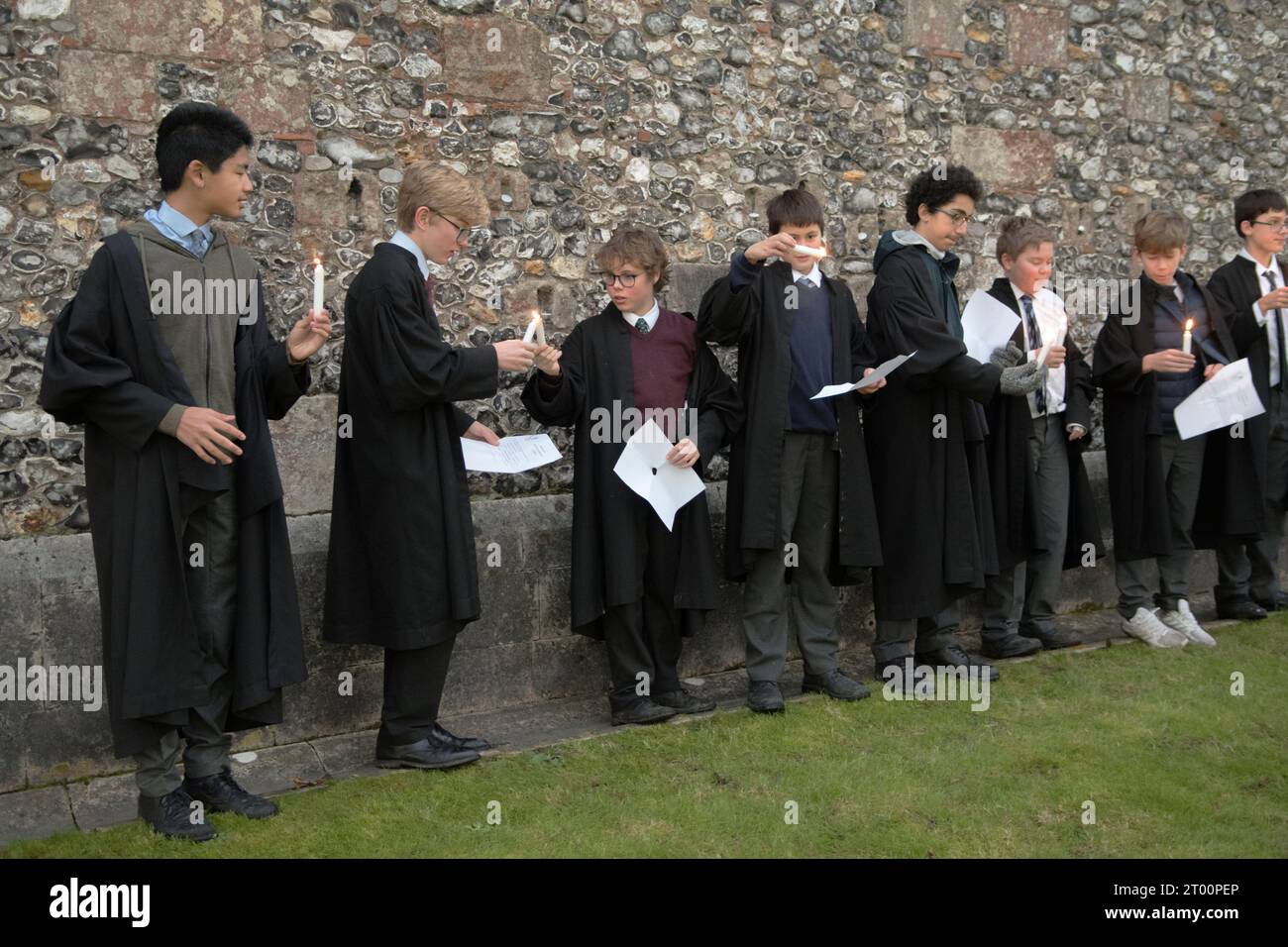 Schulpädagogik. Winchester College jährliche Illumina-Zeremonie. „College Junior Men“ Dies sind Schüler, die Gelehrte sind, Lichtkerzen in Nischen in der mittelalterlichen Meads-Mauer. (Die Wand, die ein Spielfeld umgibt.) Mit einem Schulmeister vor der Mauer sagen und singen sie einen kurzen Strophe auf Latein. Winchester, Hampshire, England, 9. Dezember 2022. HOMER SYKES AUS DEN 2020ER JAHREN. Stockfoto