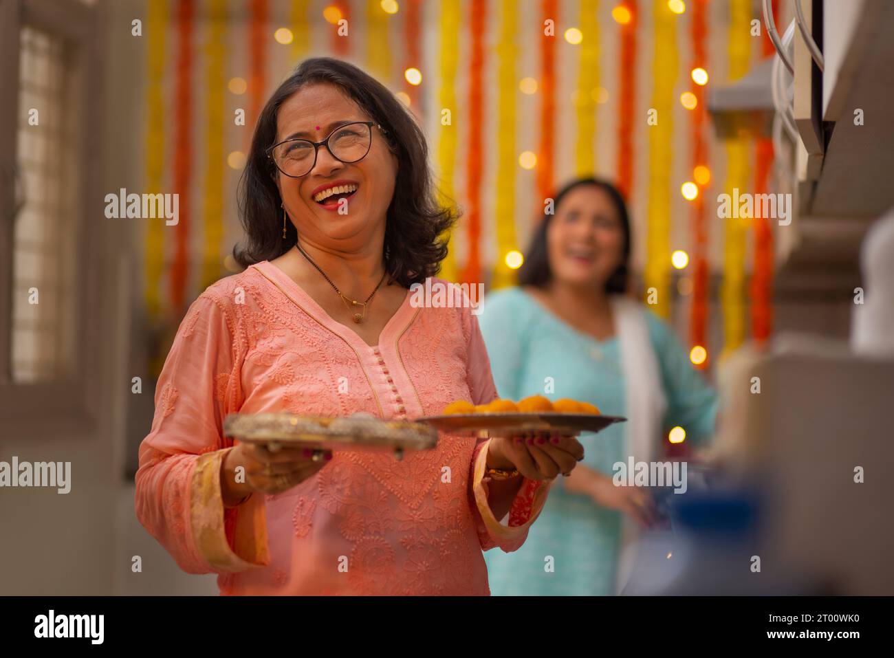 Schwiegerschwester in der Küche, bereitet sich darauf vor, Süßigkeiten während des Festivals von Diwali zu servieren Stockfoto
