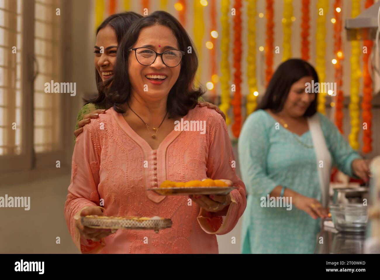 Die Damen der Familie in der Küche bereiten sich auf das Servieren von Süßigkeiten während des Festivals von Diwali vor Stockfoto