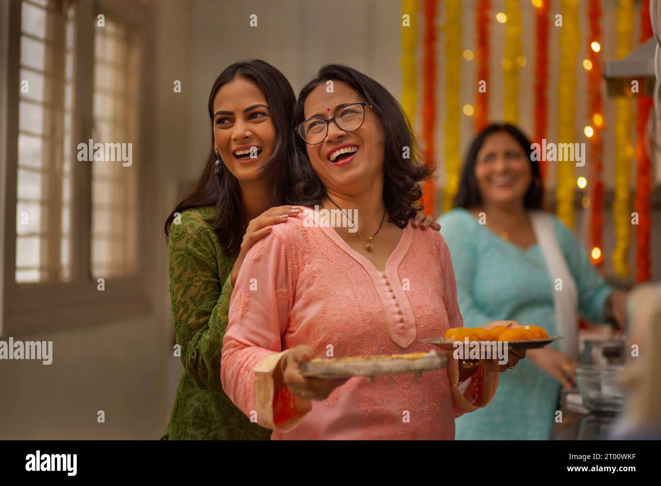Die Damen der Familie in der Küche bereiten sich auf das Servieren von Süßigkeiten während des Festivals von Diwali vor Stockfoto