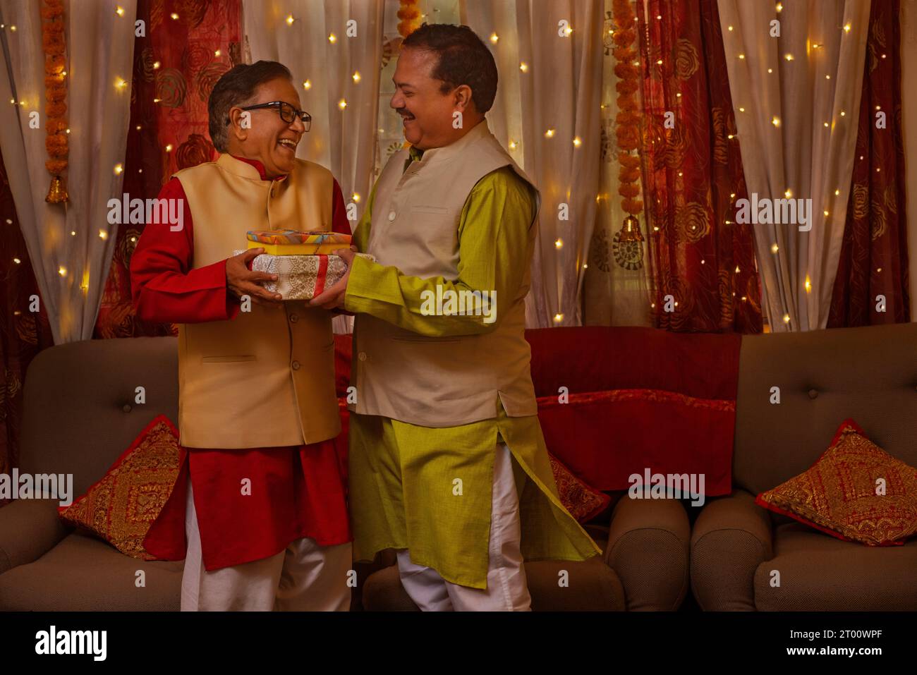 Vater und Sohn in traditionellem Outfit tauschen Geschenke aus Anlass von Diwali aus Stockfoto