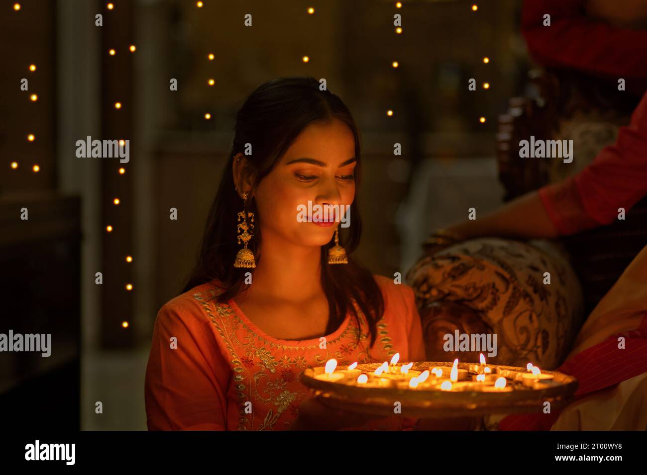Porträt einer jungen Frau, die einen Teller mit Kerzenlampen aus Anlass von Diwali hält Stockfoto