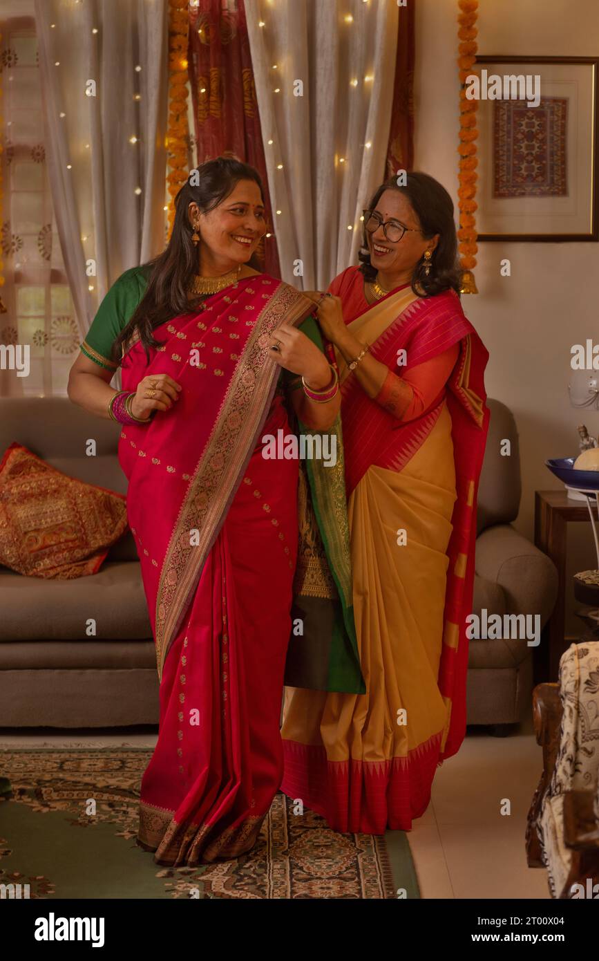 Frau, die ihrer Schwiegertochter hilft, Diwali mit Saree zu tragen Stockfoto