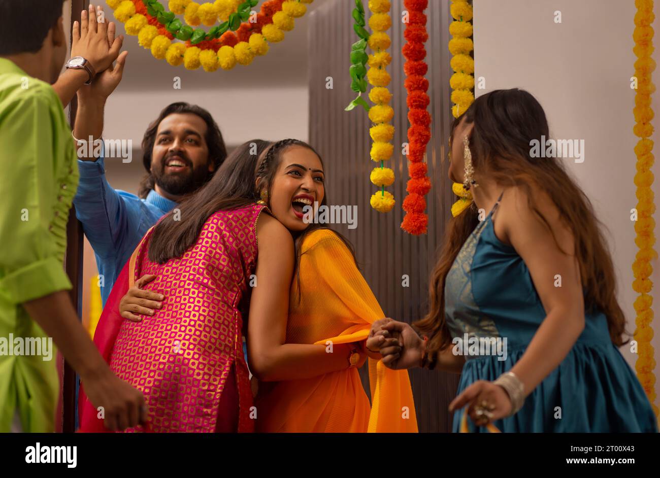 Fröhlich aufgeregtes und überraschtes Paar, das Freunde während der Diwali-Feiern am Eingang ihres eigenen Hauses begrüßt und begrüßt Stockfoto