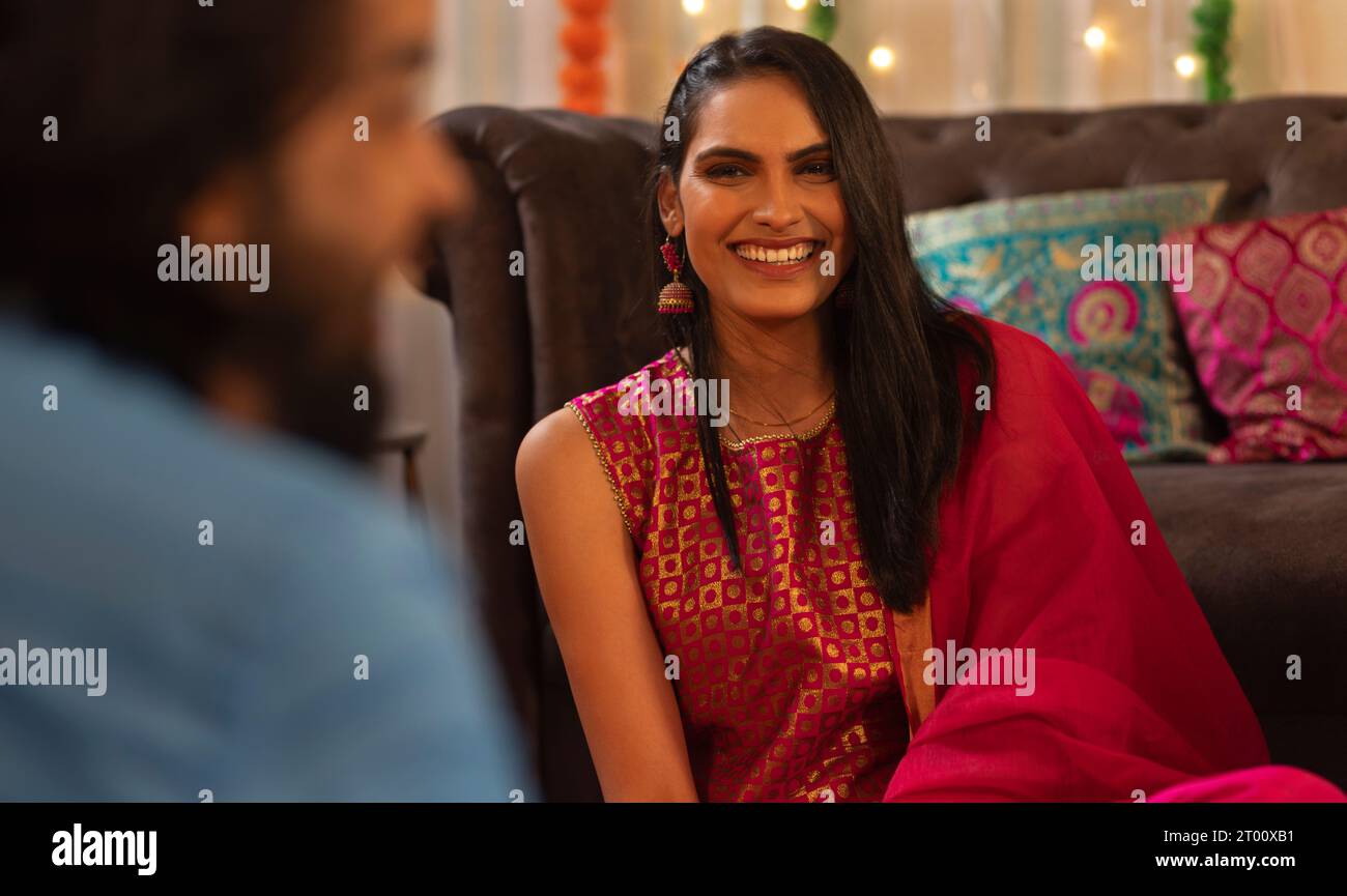 Lächelnde junge Frau genießt mit einem Freund zu Hause während der Diwali-Feier Stockfoto
