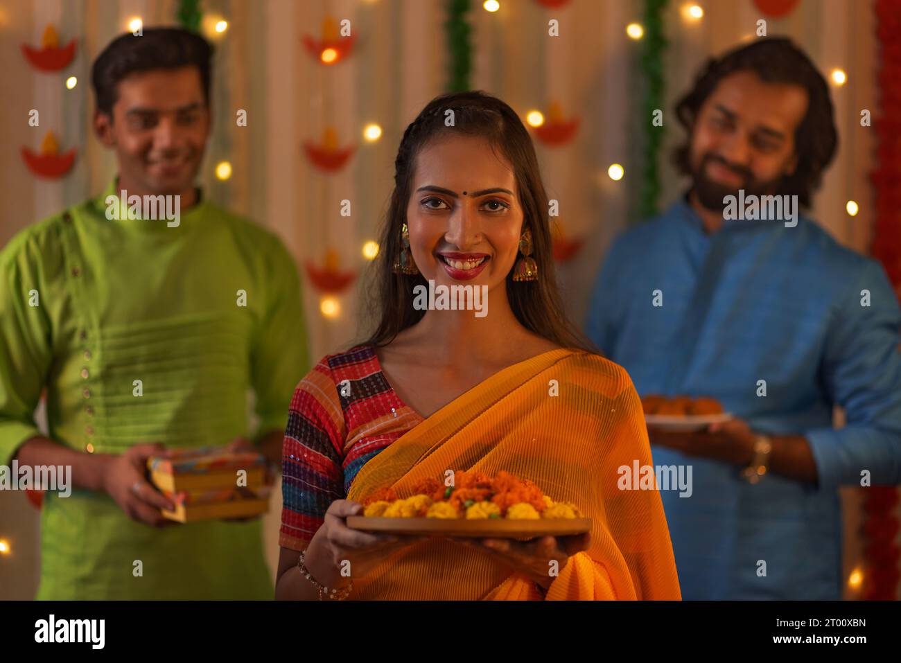 Lächelnde Frau mit Ringelblumen und ihre Freunde stehen hinter der Diwali-Feier Stockfoto