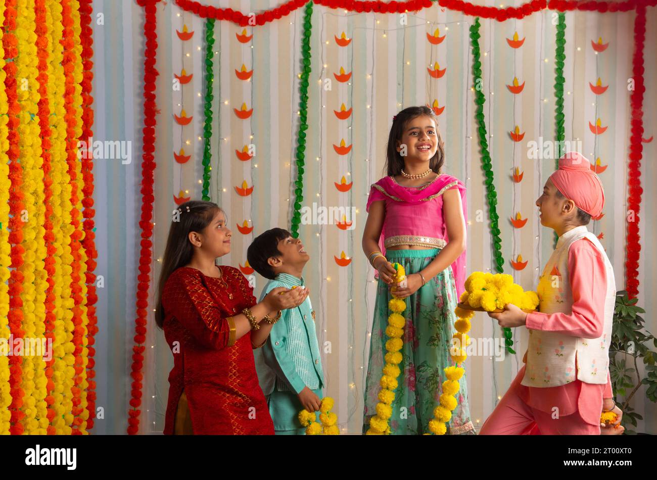 Eine Gruppe von Kindern in traditioneller Kleidung schmücken ihr Zuhause mit Blumen während der Diwali-Feiern Stockfoto