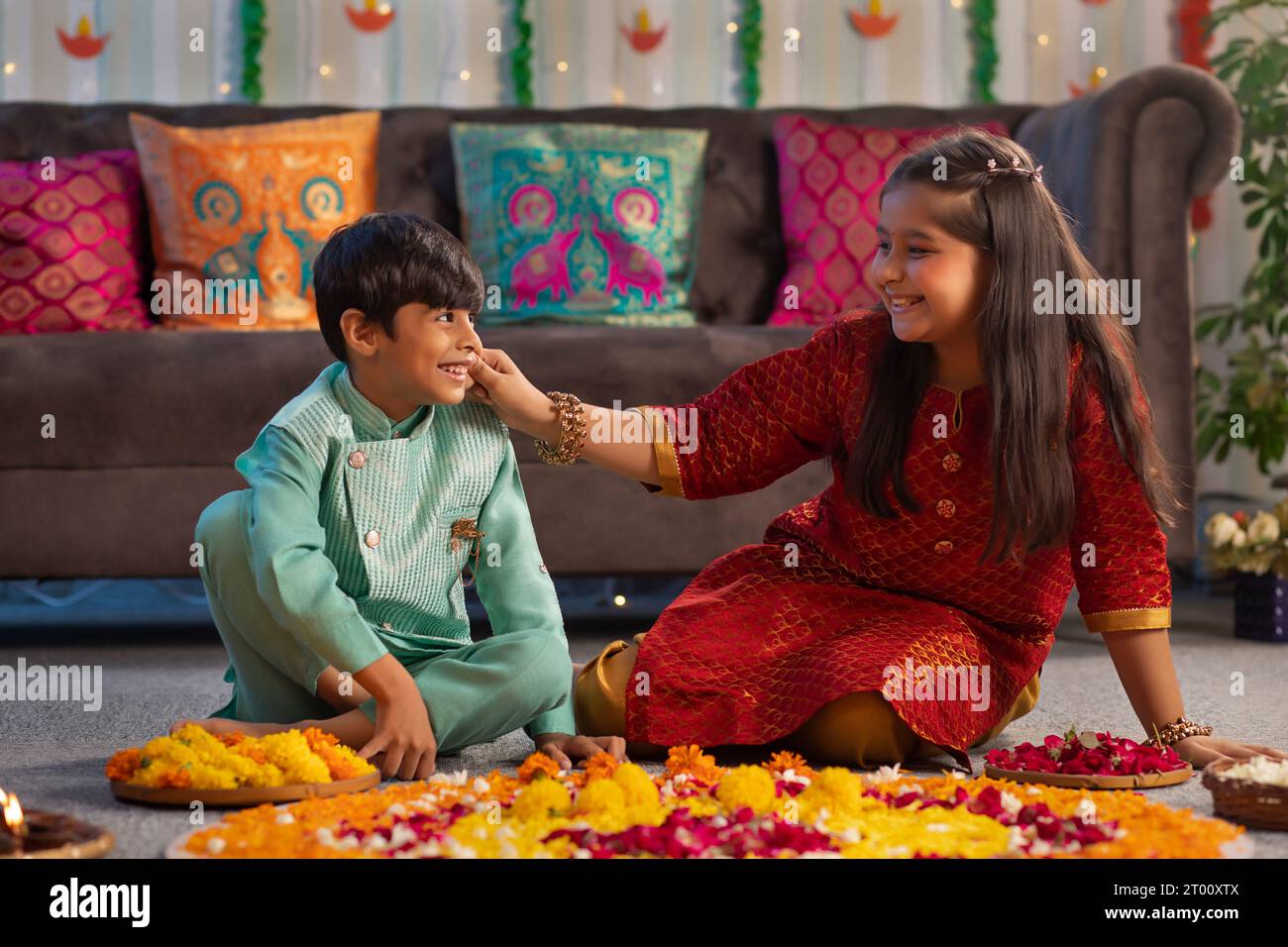 Bruder und Schwester haben Spaß beim Dekorieren des Bodens mit Blumen ( Rangoli) anlässlich von Diwali Stockfoto